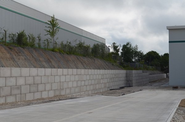 Long interlocking block retaining wall holding a planted bank beside a yard