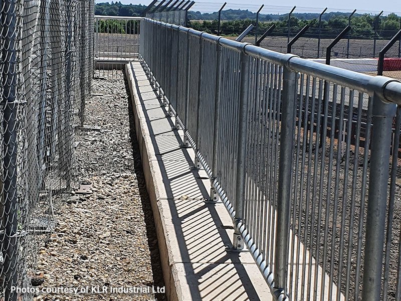 Legato block retaining wall running behind a steel palisade perimeter fence