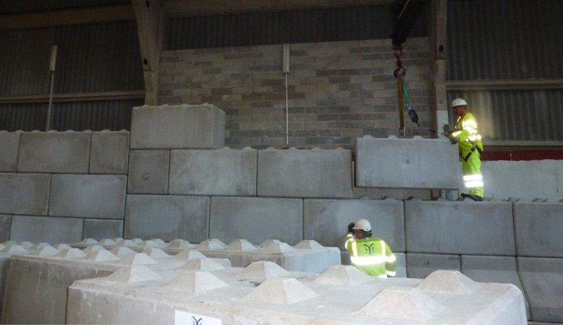Worker in hi-vis guiding a Legato block onto a part-built barn wall