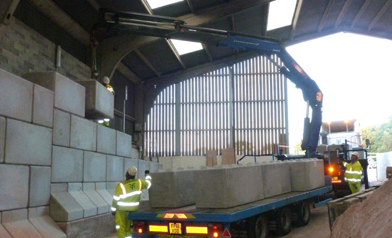 Lorry-mounted crane lifting Legato blocks from a flatbed inside a barn