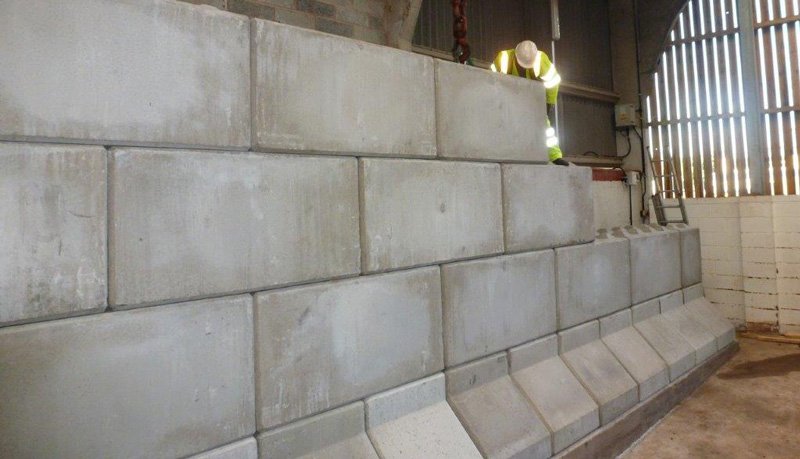 Legato block wall running the length of a barn with a worker on top