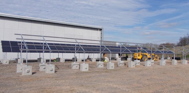 Ballast blocks supporting a solar array alongside a large distribution building