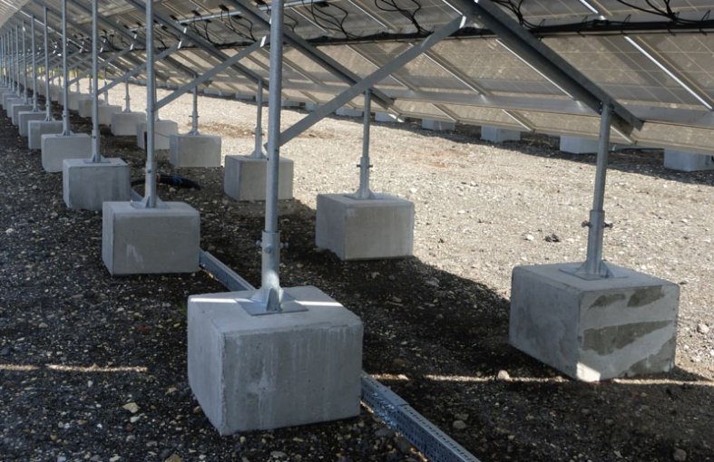 Concrete ballast blocks holding the feet of a solar panel support frame
