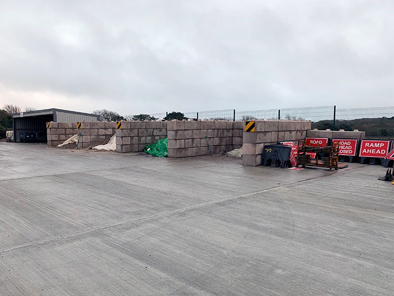 Run of interlocking block storage bays across a concrete depot yard