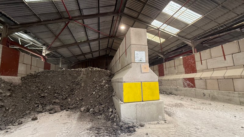 Legato bay walls and divider beside a dark aggregate stockpile inside a shed