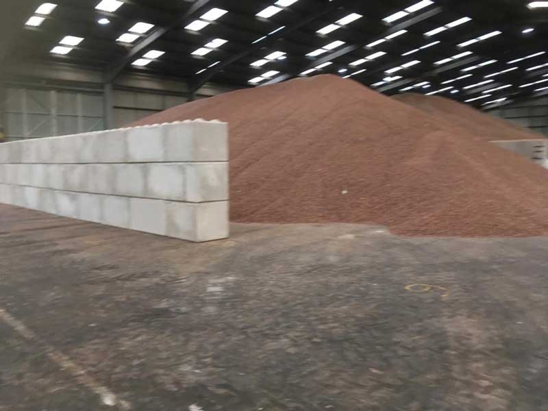 Legato block wall retaining a red sand stockpile in a storage warehouse