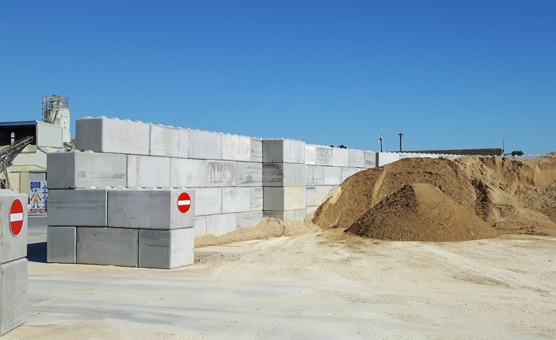 Tall Legato block walls around a sand stockpile with no-entry signage
