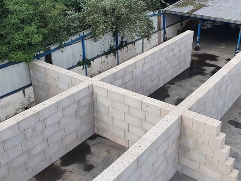 Legato interlocking blocks forming multiple divided material storage bays under a canopy