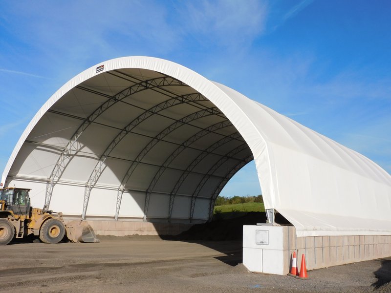 White fabric canopy building on an interlocking block plinth with a loader inside