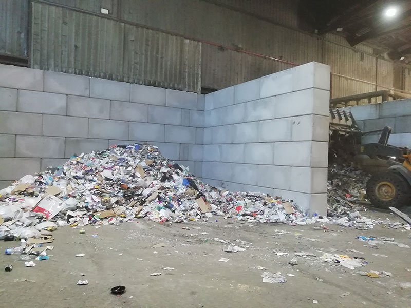 Interlocking block bay wall with waste spread across a recycling floor