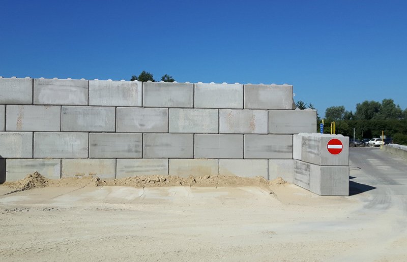 Interlocking block wall retaining sand in a storage bay under clear sky