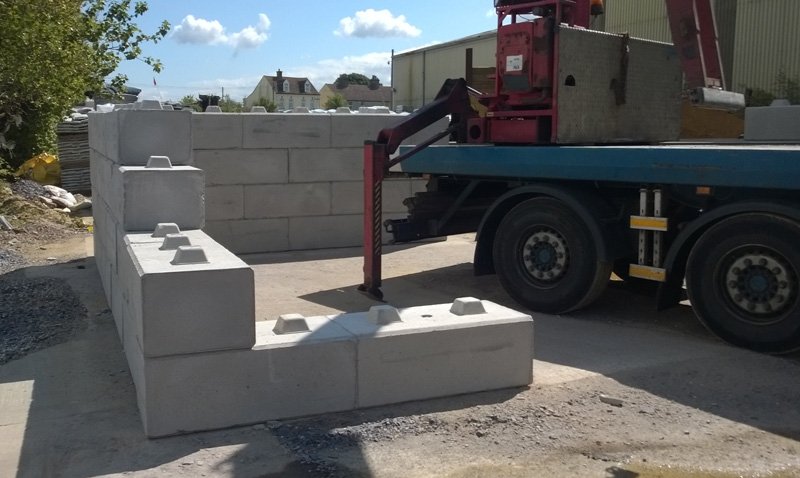 Lorry-mounted crane unloading interlocking blocks to build an aggregate bay