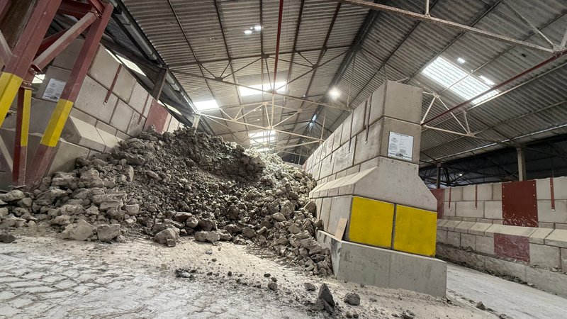 Legato block wall retaining a heap of rubble inside a storage building