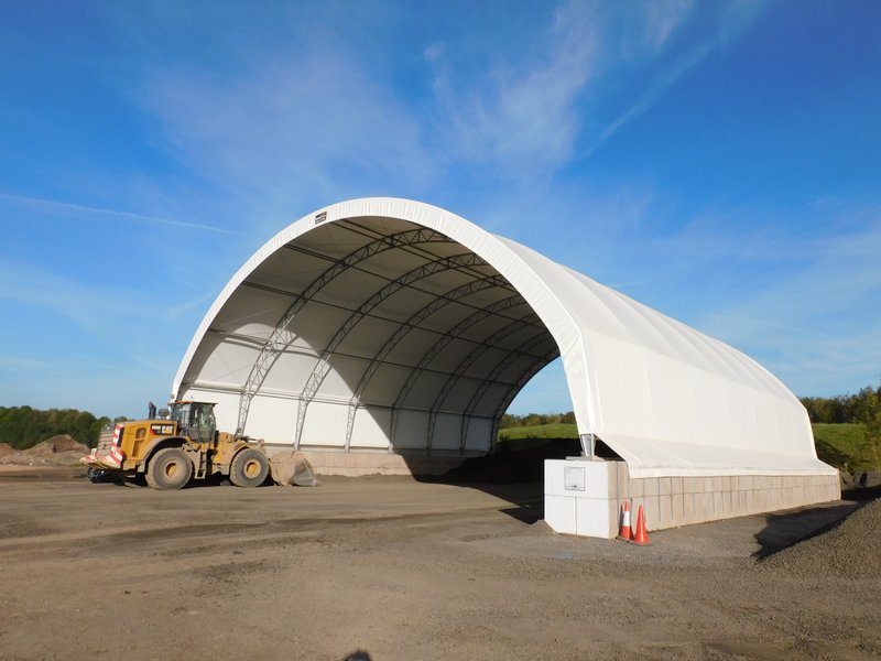 Fabric arch shelter on block walls with a loading shovel at the entrance