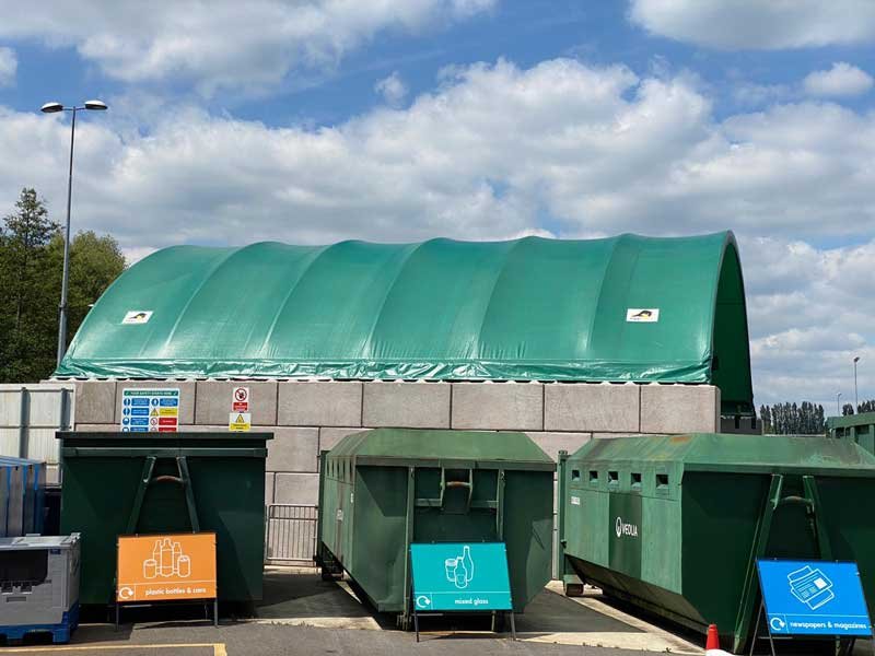 Green canopy on Legato block walls sheltering a row of recycling skips