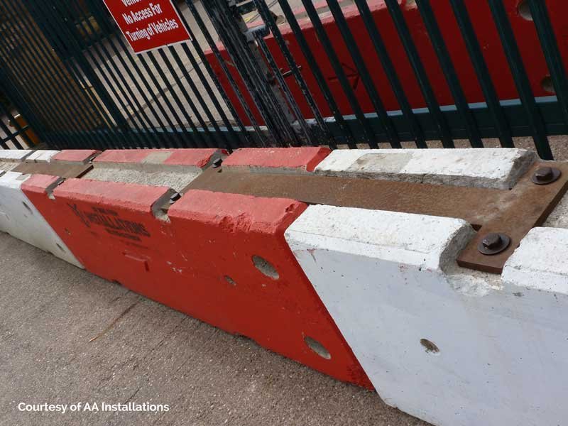 Red and white TVCB barriers bolted together across a site entrance