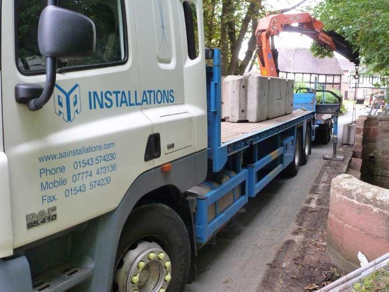 Installation lorry loaded with precast barrier units on a narrow lane