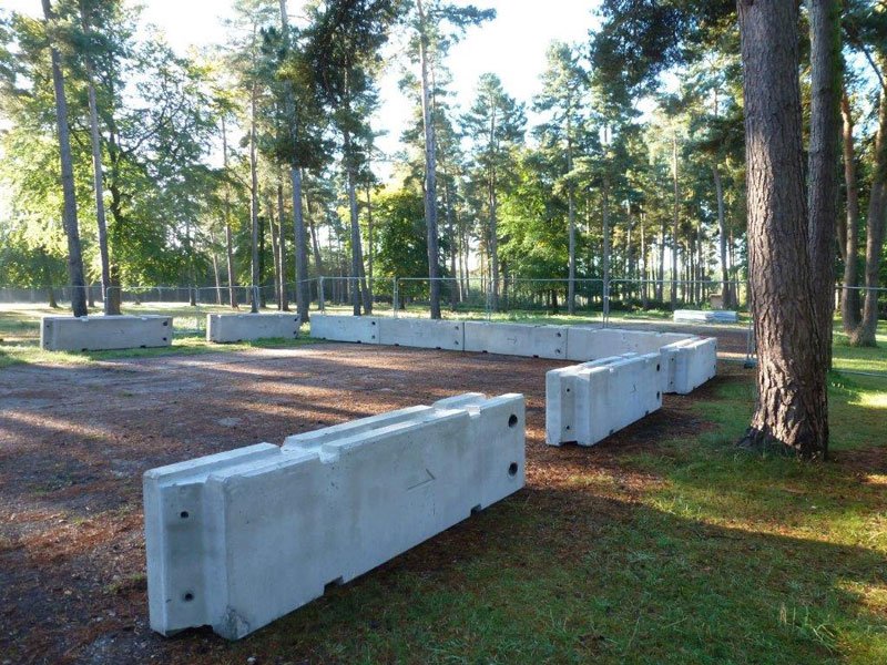 Line of temporary vertical concrete barriers laid along a woodland track