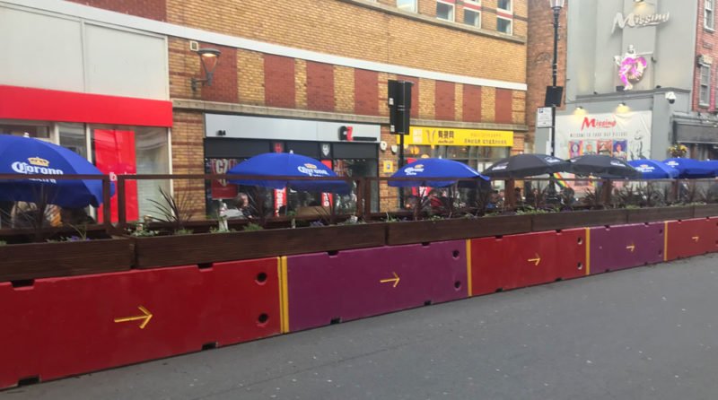 Red-clad TVCB barriers protecting a high street pavement seating area
