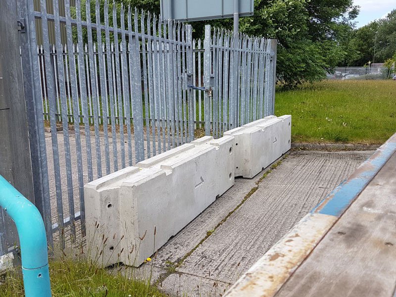 TVCB barriers installed along a palisade fence beside a blue service pipe