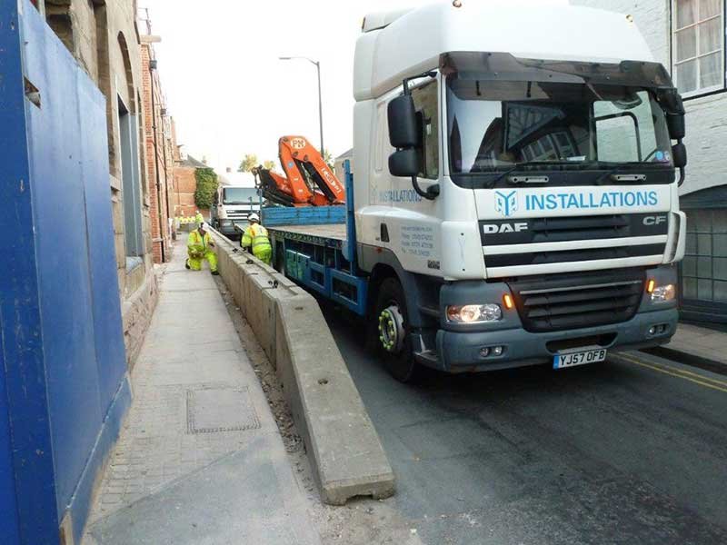 TVCB barriers being installed along a narrow street from a crane lorry