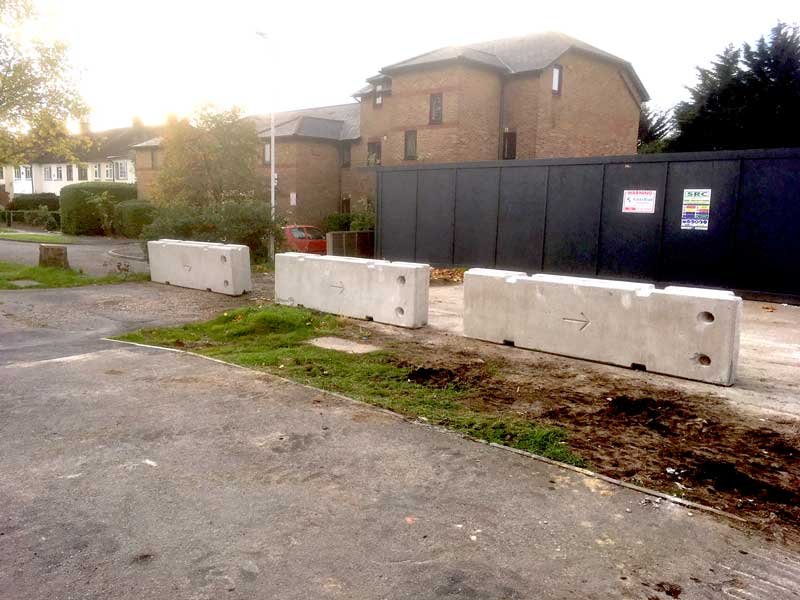 Temporary vertical concrete barriers protecting hoarding beside newly built houses
