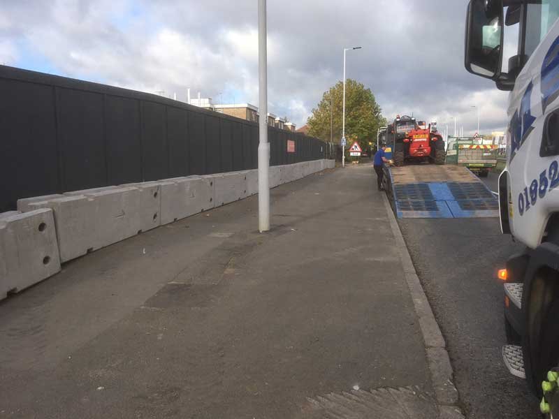 Line of TVCB barriers separating a footway from the road past a lorry