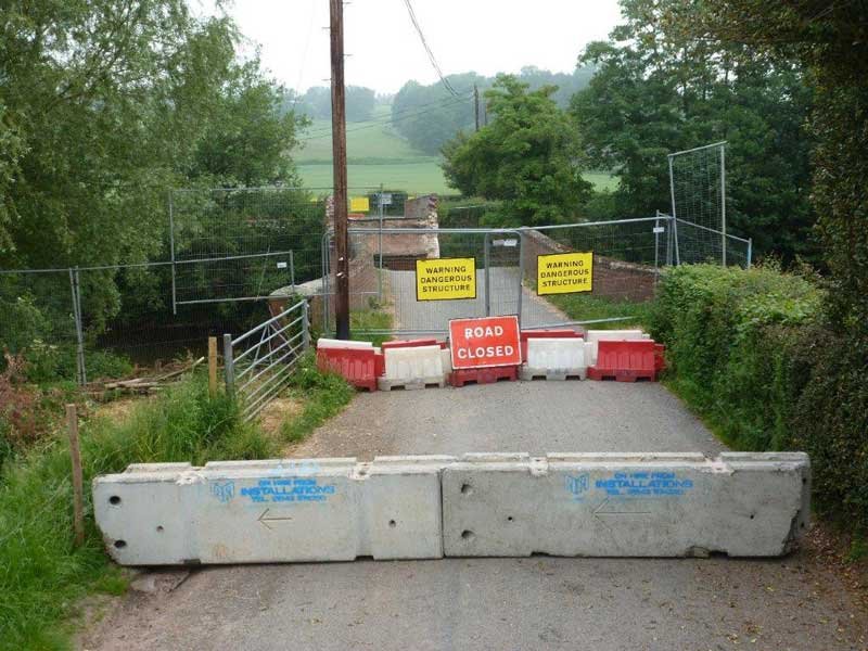 TVCB barriers blocking a rural lane beside a road closed sign
