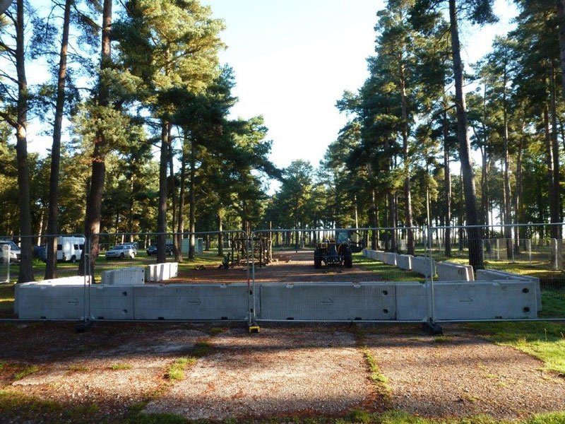 Line of TVCB barriers and fencing forming a boundary in pine woodland