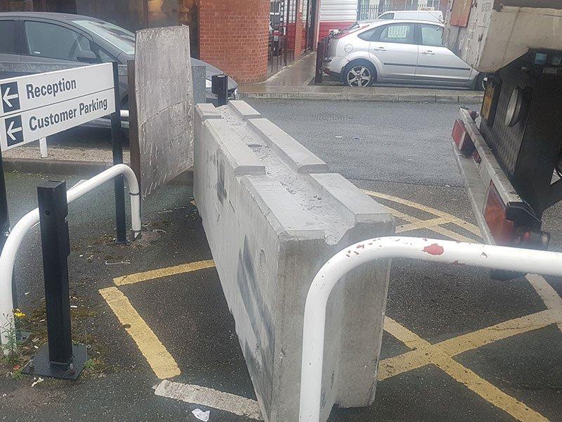 Temporary vertical concrete barrier beside a reception and customer parking entrance
