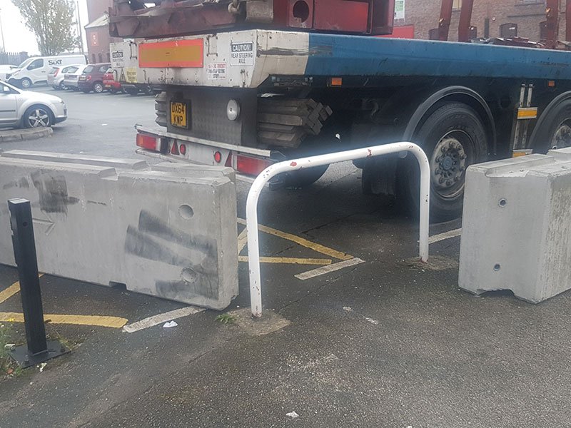 Temporary vertical concrete barriers set in a car park beside a parked trailer