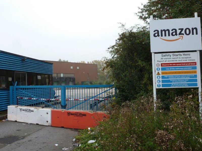 TVCB barriers closing a gated entrance beside an Amazon site sign