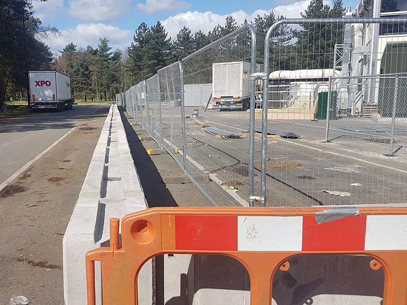 Long line of concrete barriers and fencing beside an industrial estate road