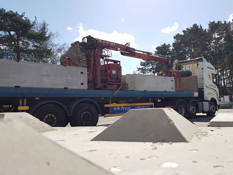Flatbed lorry loaded with temporary vertical concrete barriers waiting to be offloaded