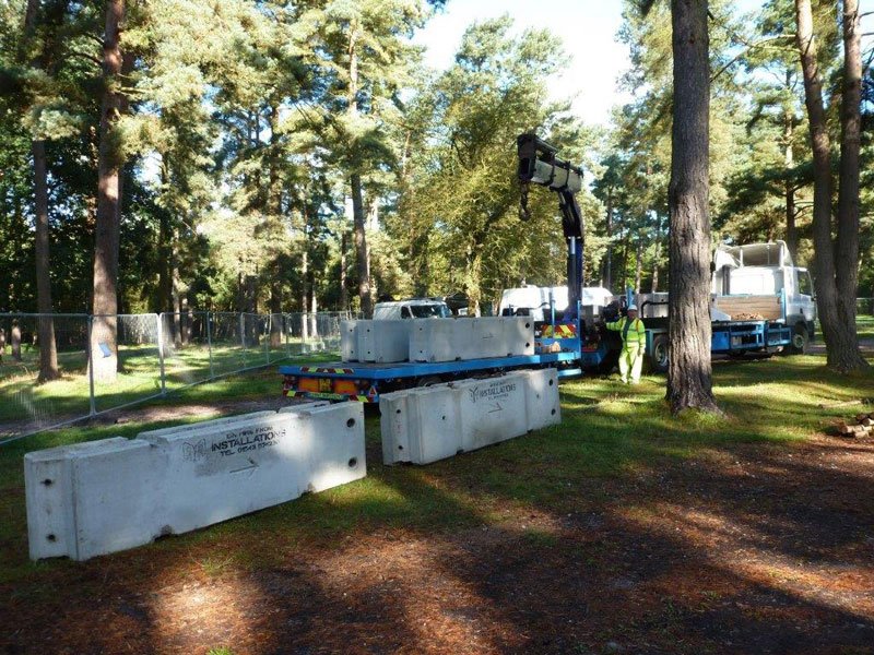 Temporary vertical concrete barriers positioned across woodland for event traffic control