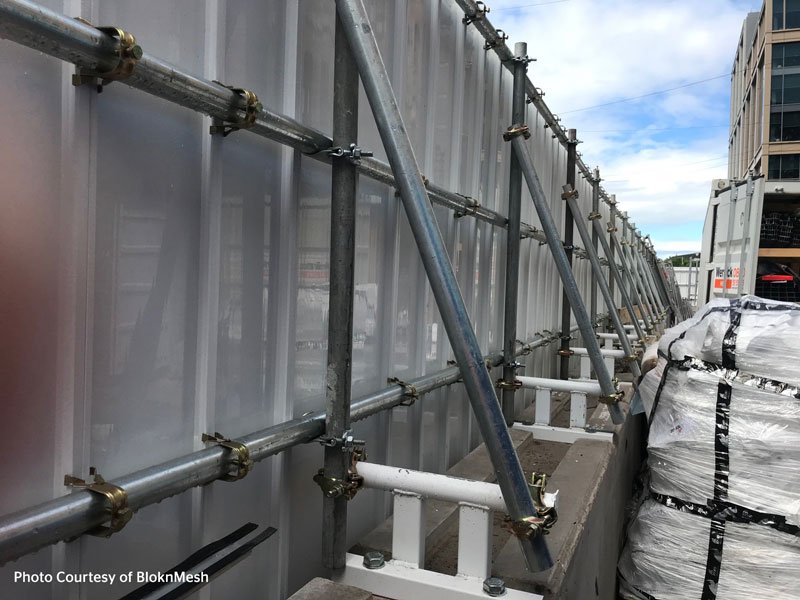 Concrete barriers weighting a scaffold braced site hoarding beside a city building