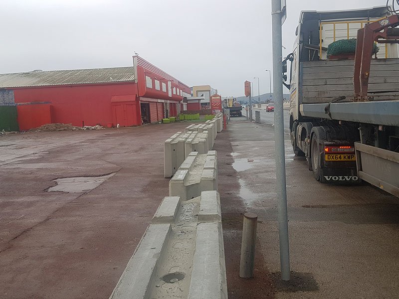 Line of concrete barriers edging a yard roadway beside a parked lorry
