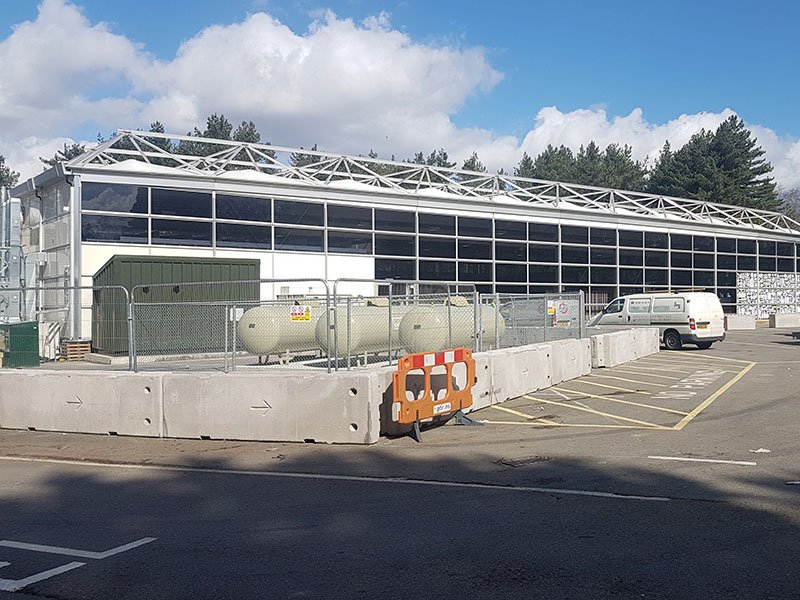 Concrete barriers protecting storage tanks outside a large commercial building
