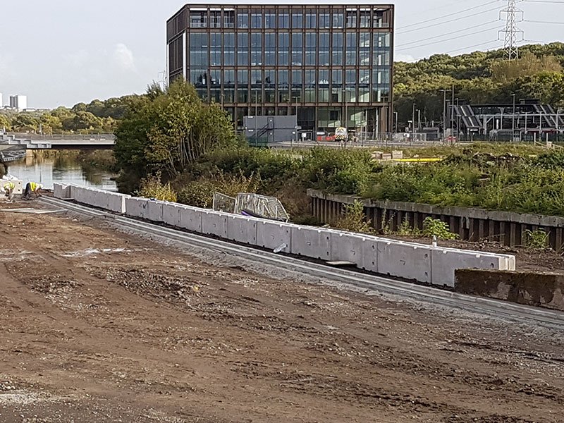 Concrete barriers lining a riverside construction site below an office building