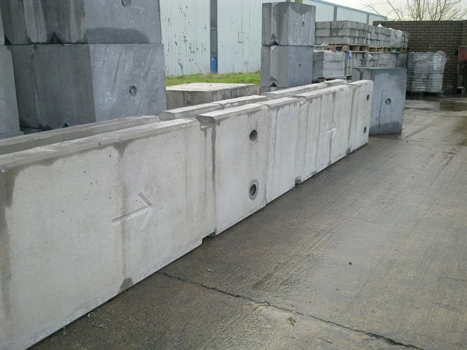 Run of temporary vertical concrete barriers lining a narrow yard access road