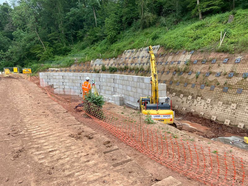 Legato blocks forming a retaining wall on a wooded hillside during construction
