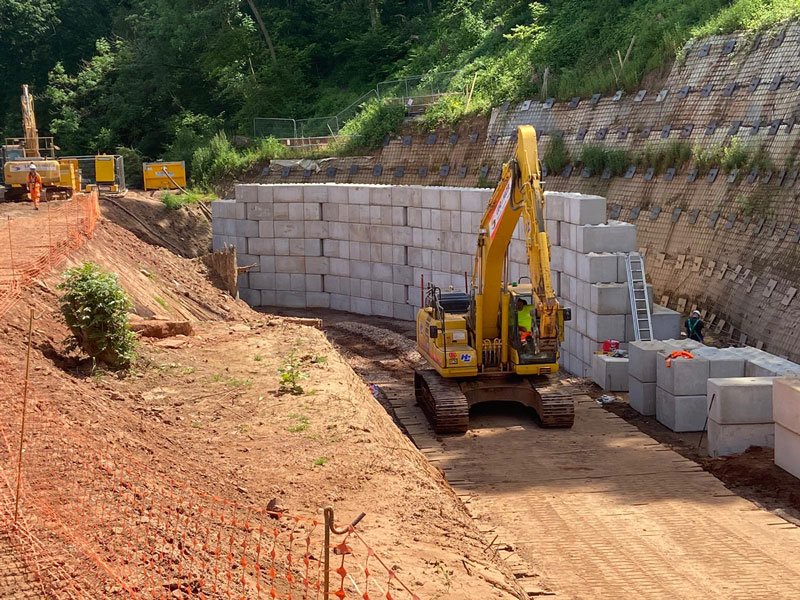 Excavator placing Legato interlocking blocks to build a river channel wall