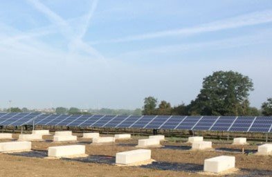 Ballast blocks set out in a field in front of an existing solar array