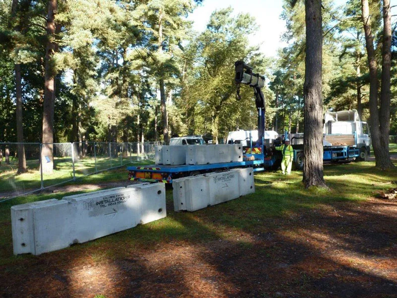 TVCB barriers being craned into place along a wooded parkland road