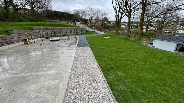 Block retaining wall terracing a holiday park lawn beside a gravel footpath