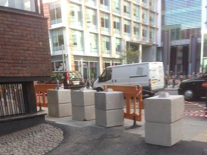 Kentledge ballast blocks weighting temporary barriers along a city street