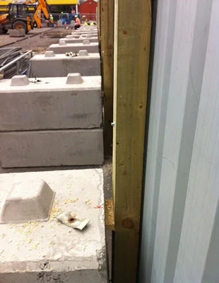 Kentledge ballast blocks lining the base of a timber site hoarding