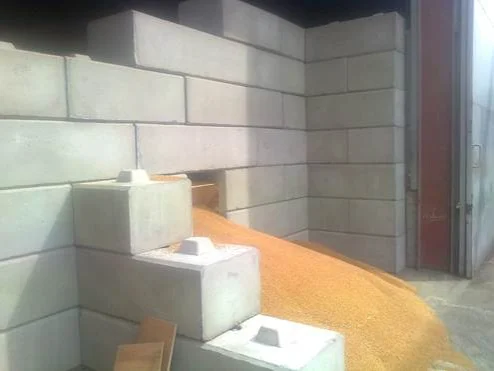 Duo blocks forming the walls of a farm storage bay with loose grain heaped inside