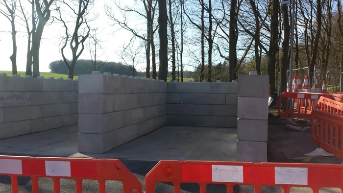 Three-sided material storage bay built from Duo blocks behind red safety barriers