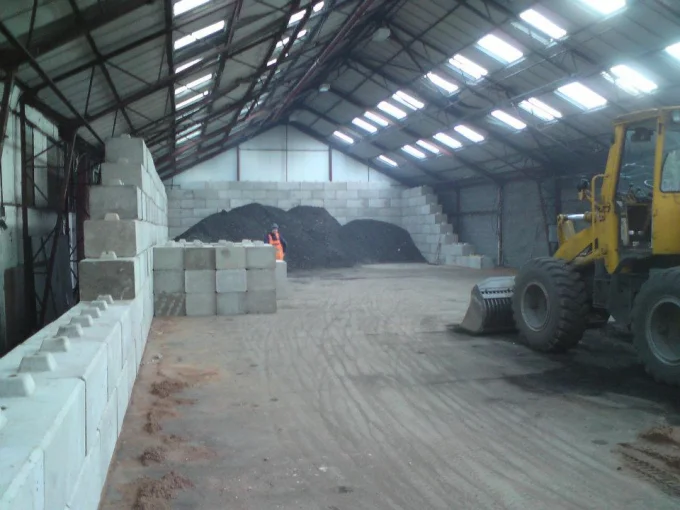 Loading shovel working between Duo block storage bay walls inside an aggregate shed